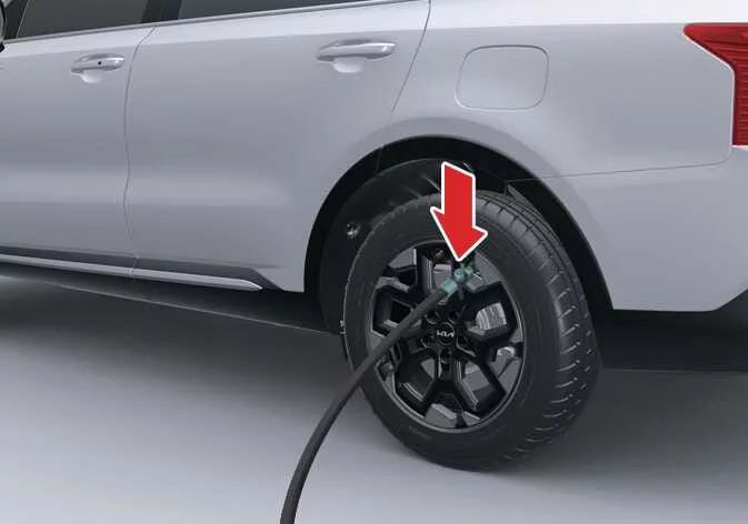 Attaching the sealant filling hose to the flat tire valve on a Kia Sorento