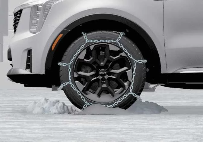 Close-up view of wire-type snow chains properly fitted on a Kia Sorento tire